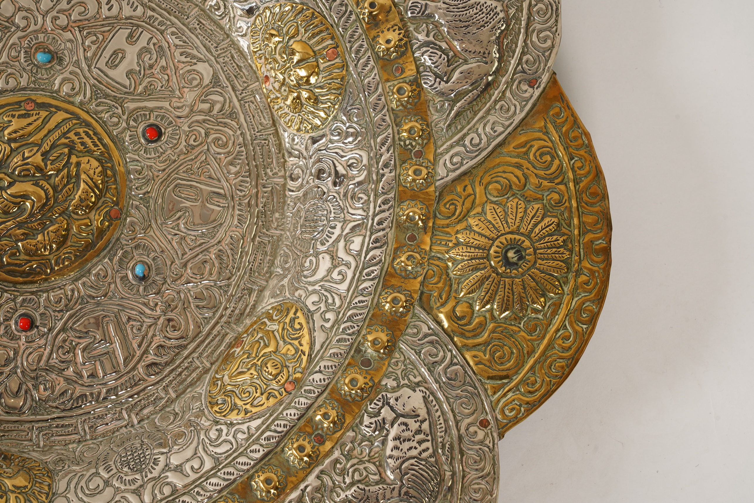 A graduated set of three Nepalese repoussé white metal and brass chargers, first half 20th century